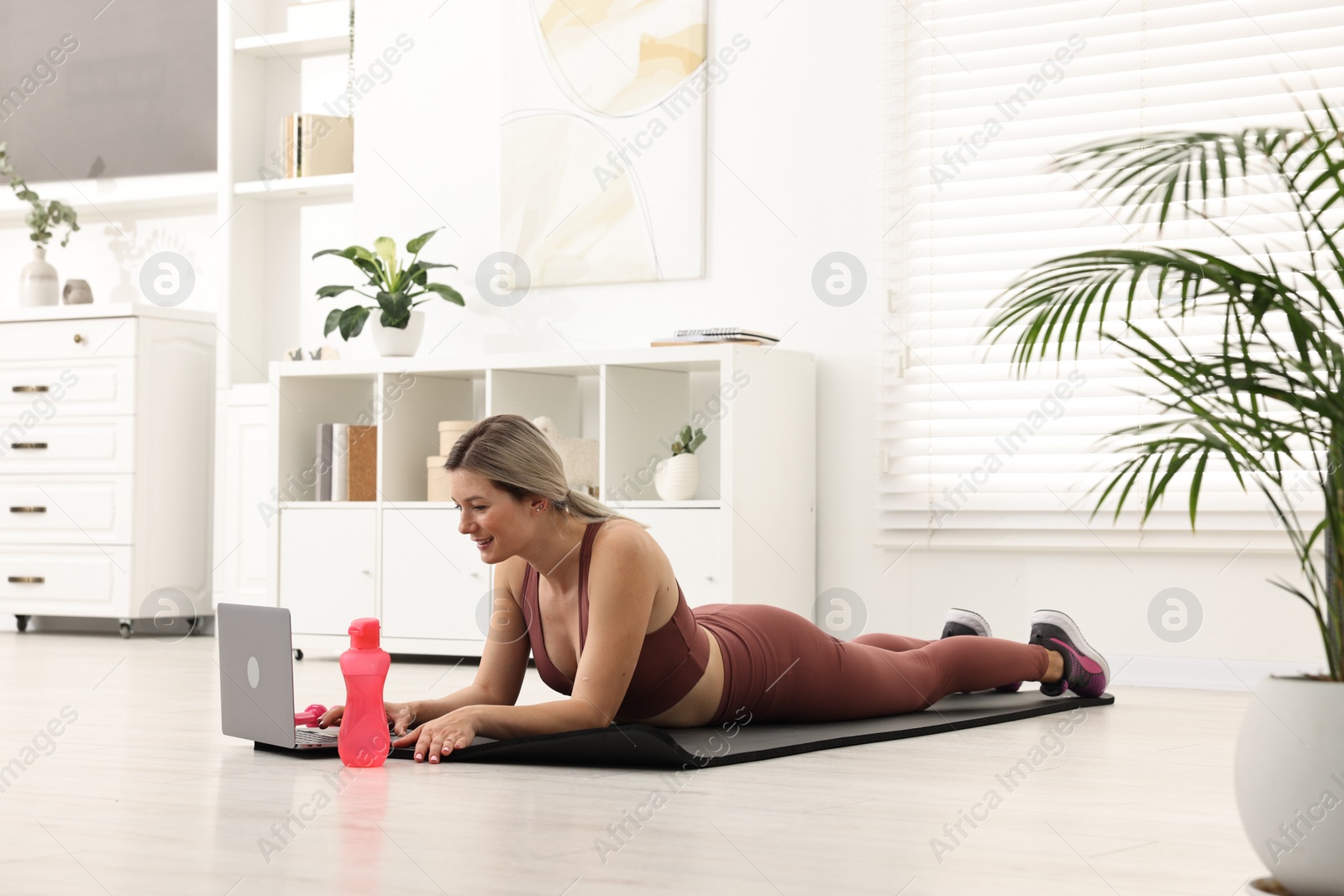 Photo of Online fitness trainer. Woman watching tutorial on laptop at home