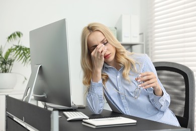 Overwhelmed woman with glasses at table in office