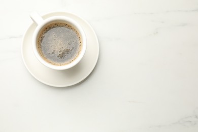 Photo of Cup of aromatic coffee on white table, top view. Space for text