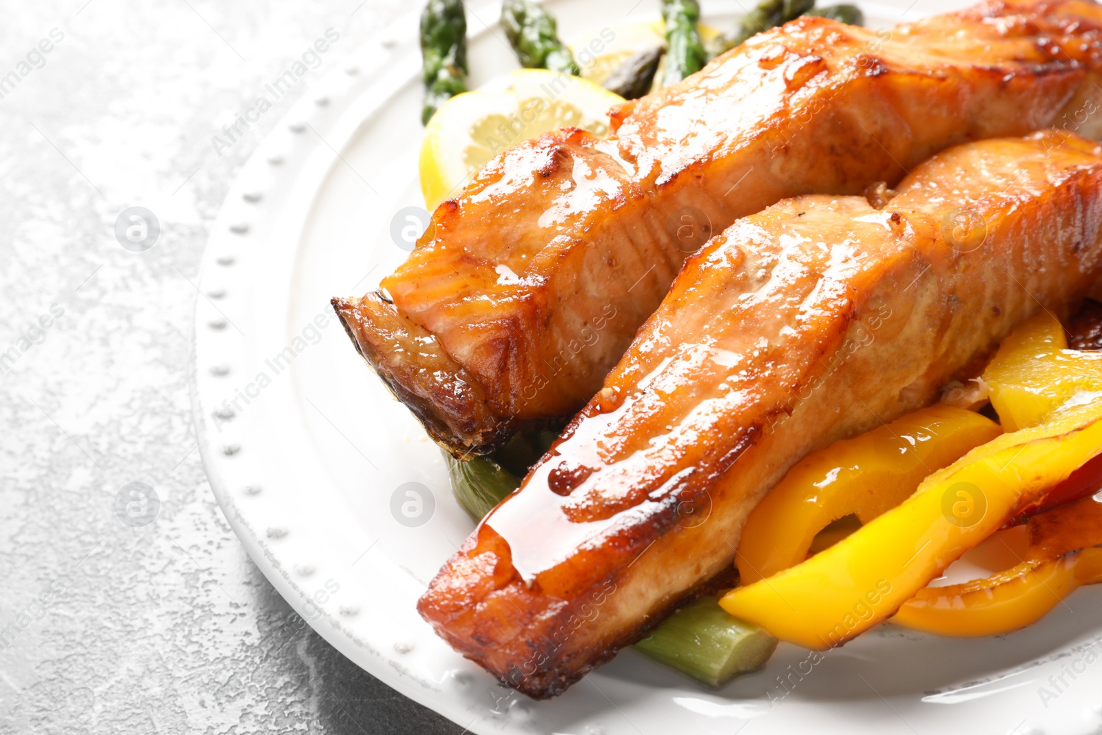 Photo of Tasty cooked salmon with vegetables on plate, closeup