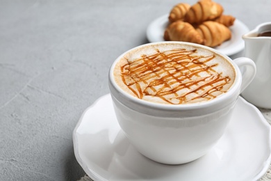 Cup of caramel macchiato and tasty pastry on table