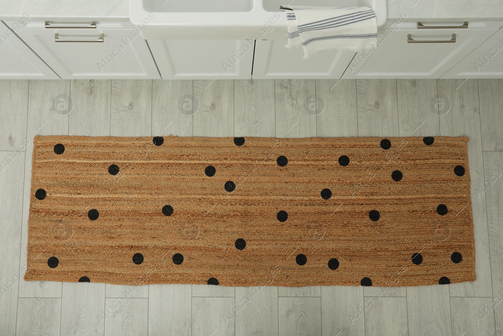 Photo of Stylish rug with dots on floor in kitchen, above view