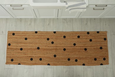 Stylish rug with dots on floor in kitchen, above view
