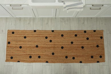 Photo of Stylish rug with dots on floor in kitchen, above view