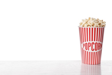 Delicious popcorn in paper cup on white wooden table