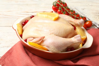 Photo of Chicken with orange slices and red berries on white wooden table