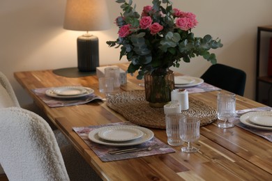 Photo of Beautiful table setting with bouquet and candles indoors. Roses and eucalyptus branches in vase