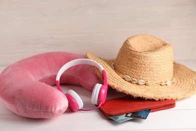 Photo of Pink travel pillow, hat, headphones and wallet with credit cards on light wooden background