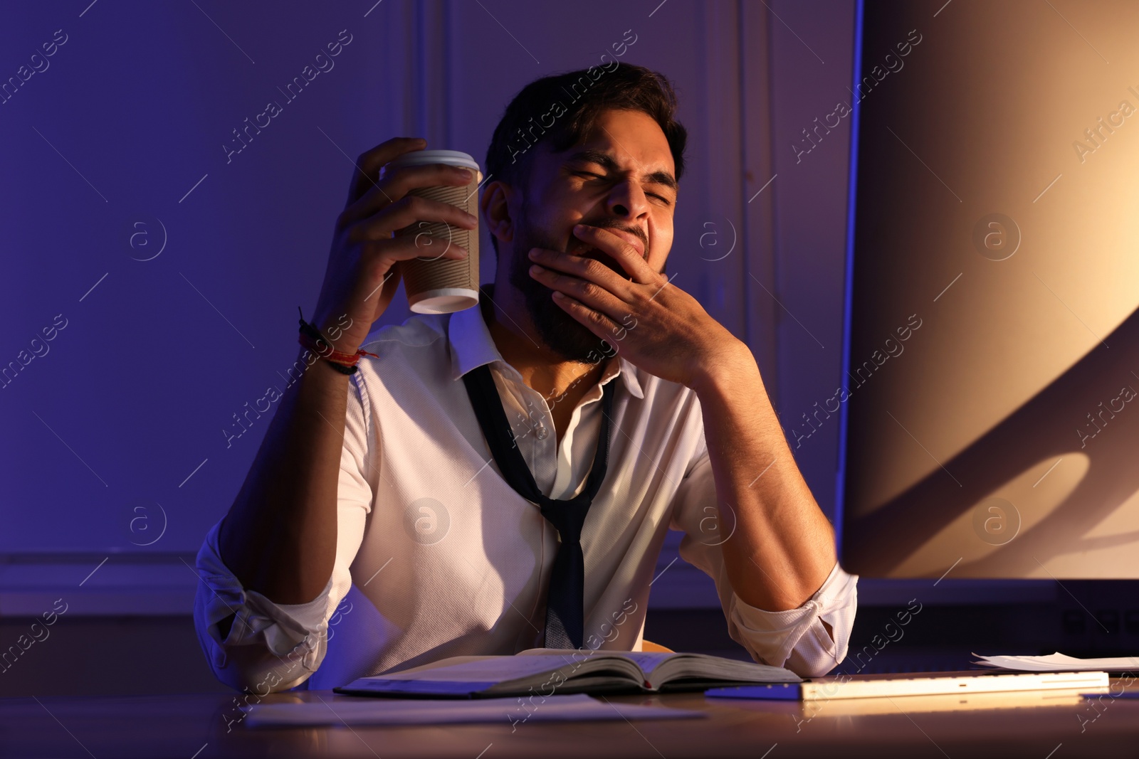 Photo of Tired man with coffee working late in office