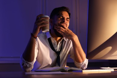 Photo of Tired man with coffee working late in office