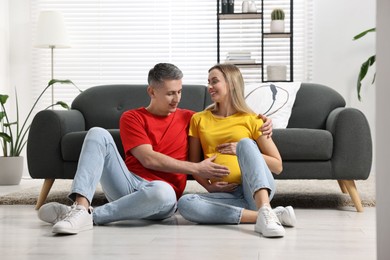 Young family housing concept. Pregnant woman with her husband on floor at home