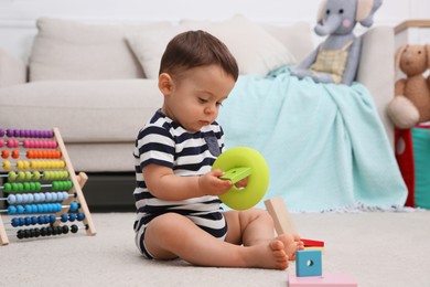 Photo of Cute baby boy playing with toys on floor at home