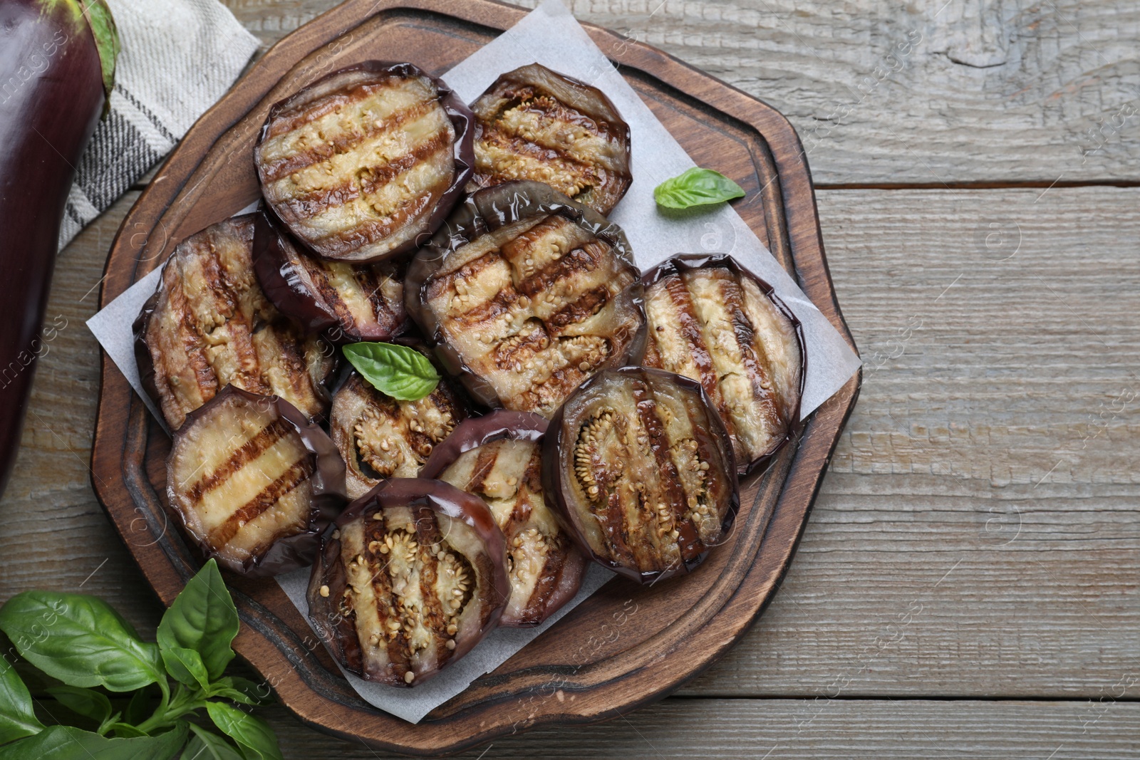 Photo of Delicious grilled eggplant slices served on wooden table, flat lay