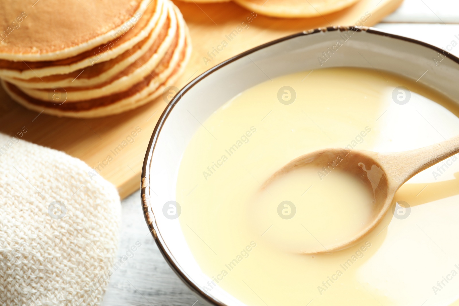 Photo of Bowl with condensed milk on table, closeup. Dairy products