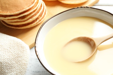 Photo of Bowl with condensed milk on table, closeup. Dairy products