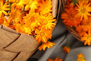 Beautiful fresh calendula flowers in wicker bag on table, above view