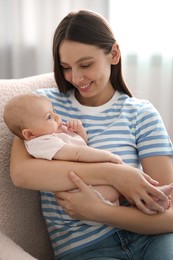 Photo of Mother with her cute baby in armchair at home