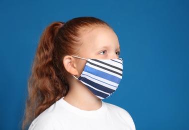 Preteen girl in protective face mask on blue background