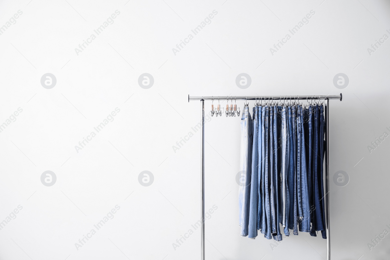 Photo of Rack with different jeans on white background. Space for text