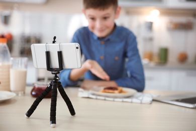 Photo of Cute little blogger with food recording video on kitchen