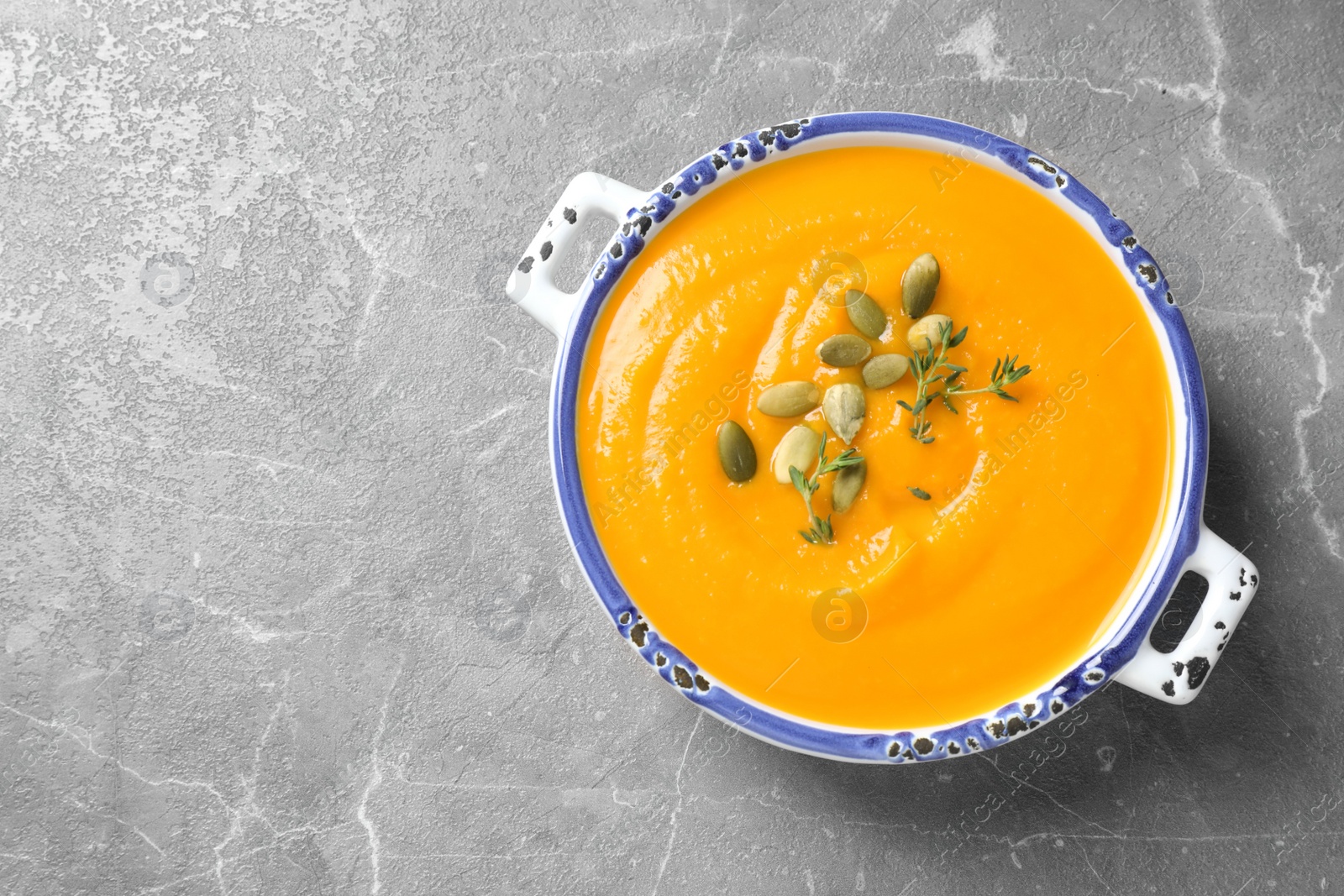 Photo of Delicious pumpkin soup in bowl on marble table, top view. Space for text
