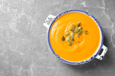 Delicious pumpkin soup in bowl on marble table, top view. Space for text