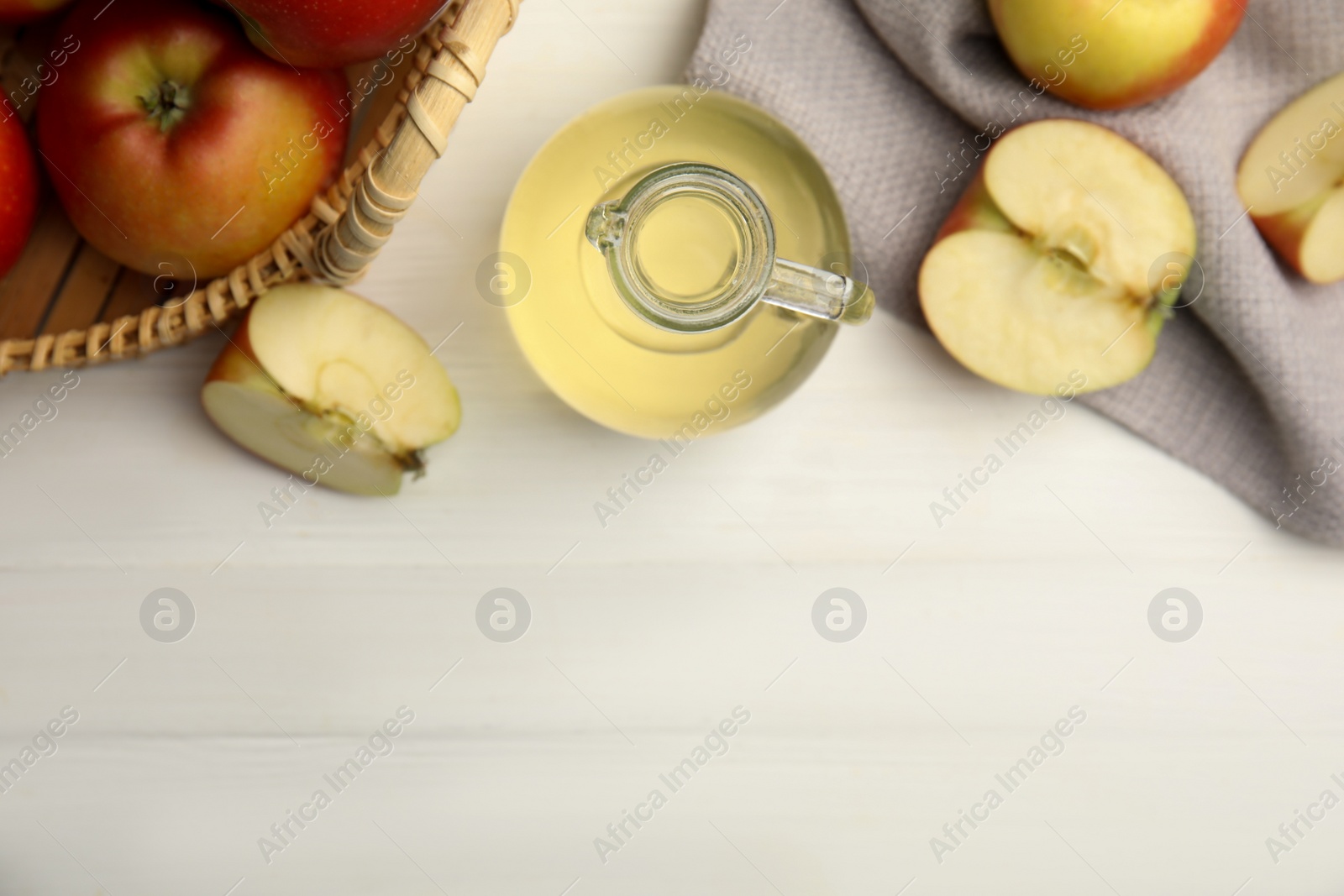 Photo of Natural apple vinegar and fresh fruits on white wooden table, flat lay. Space for text