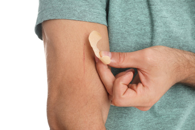Man putting sticking plaster onto arm against on background, closeup