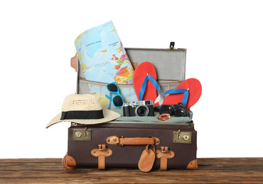 Photo of Open vintage suitcase with clothes packed for summer vacation on wooden table against white background