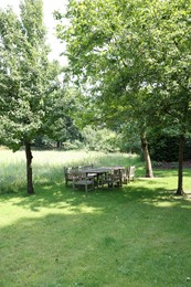 Photo of Empty wooden table with bench and chairs in garden