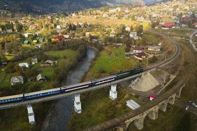 Image of Aerial view of train on bridge and village