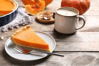 Photo of Plate with piece of fresh delicious homemade pumpkin pie on wooden table