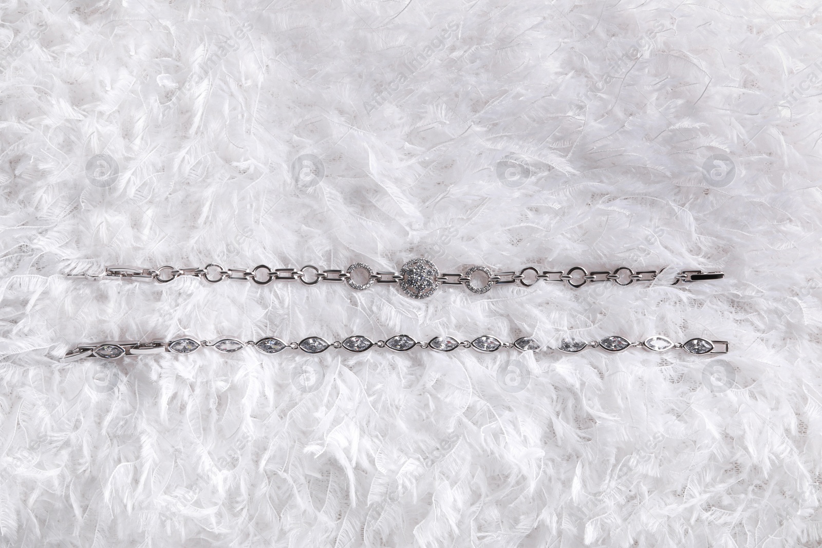 Photo of Luxury jewelry. Elegant bracelets on white feathers, flat lay