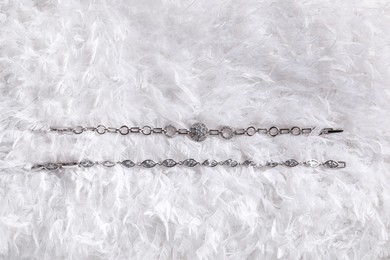 Luxury jewelry. Elegant bracelets on white feathers, flat lay