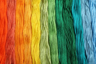 Different colorful embroidery threads as background, top view