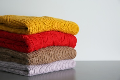 Photo of Stack of folded knitted sweaters on grey table