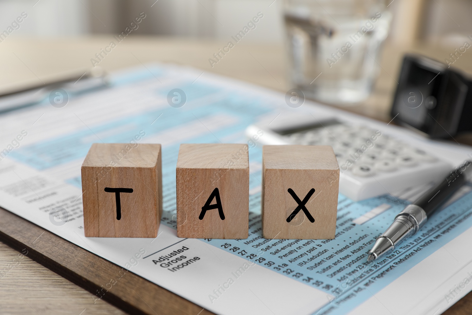 Photo of Wooden cubes with word Tax and document on table, closeup