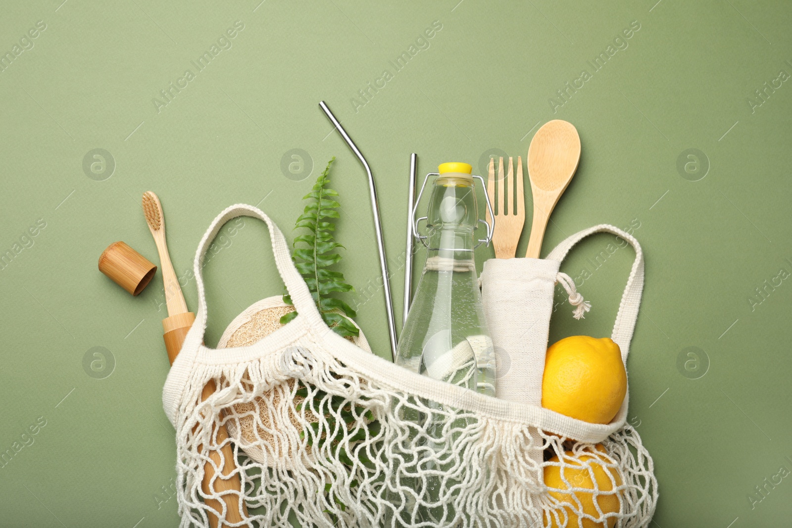 Photo of Bag with eco friendly products on green background, top view