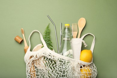 Photo of Bag with eco friendly products on green background, top view