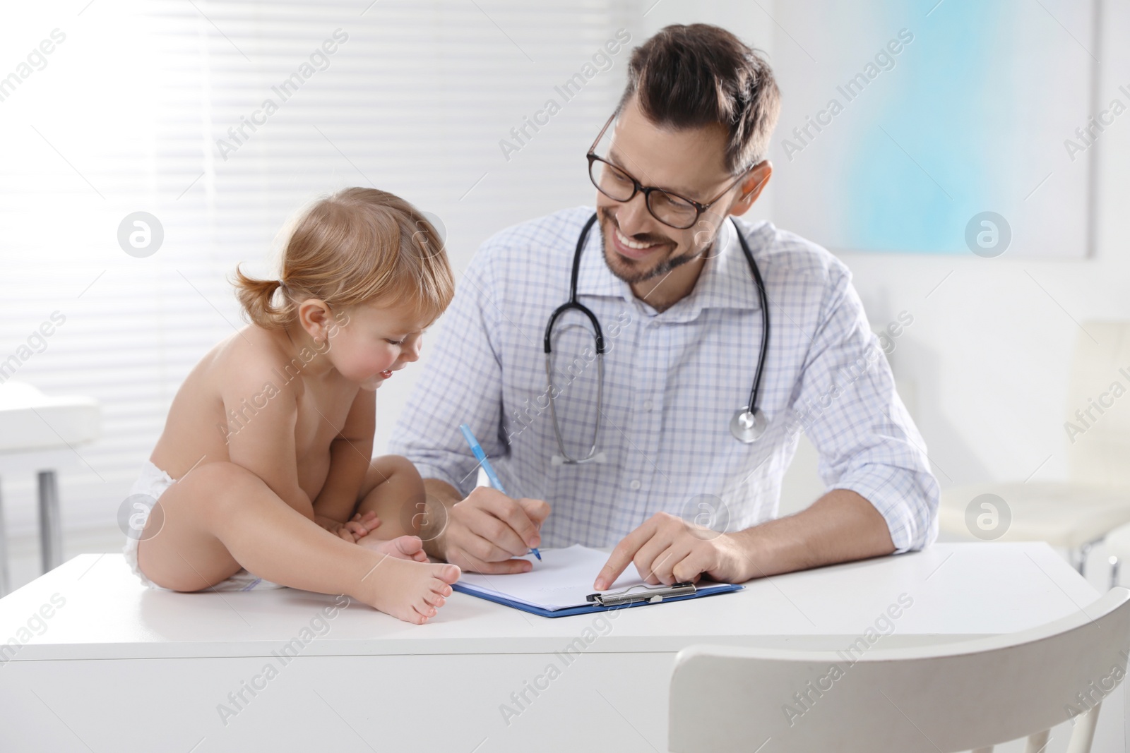 Photo of Pediatrician examining cute little baby in clinic