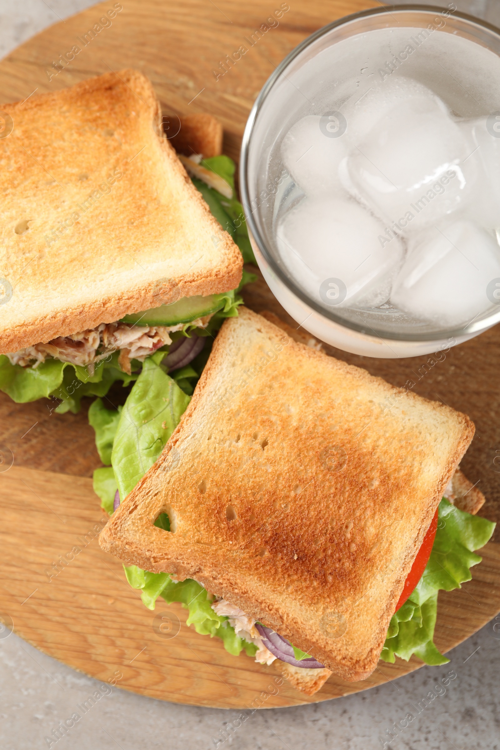 Photo of Delicious sandwiches with tuna, vegetables and glass of cold water on light grey table, flat lay