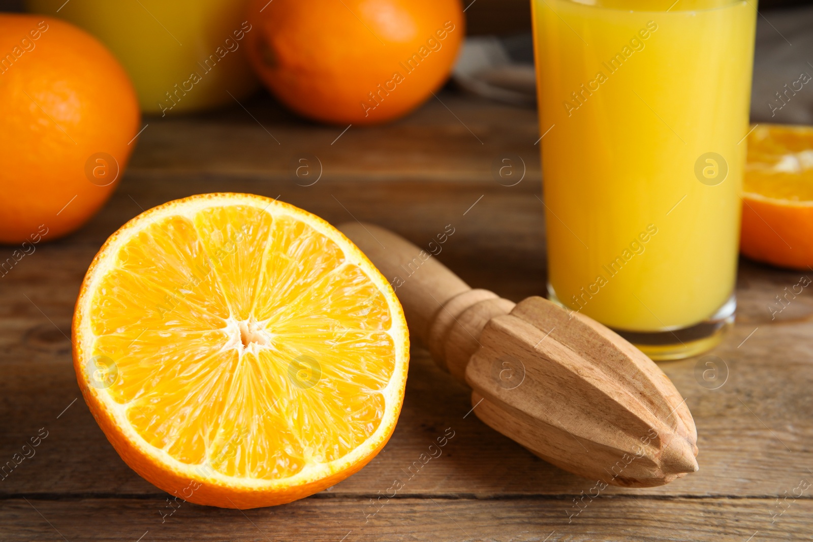 Photo of Cut fresh ripe orange, reamer and juice on wooden table, closeup