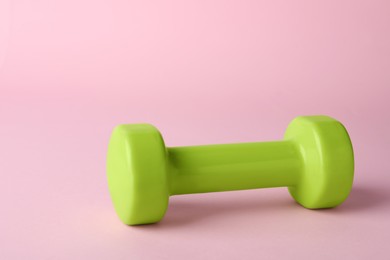 Photo of One green dumbbell on light pink background