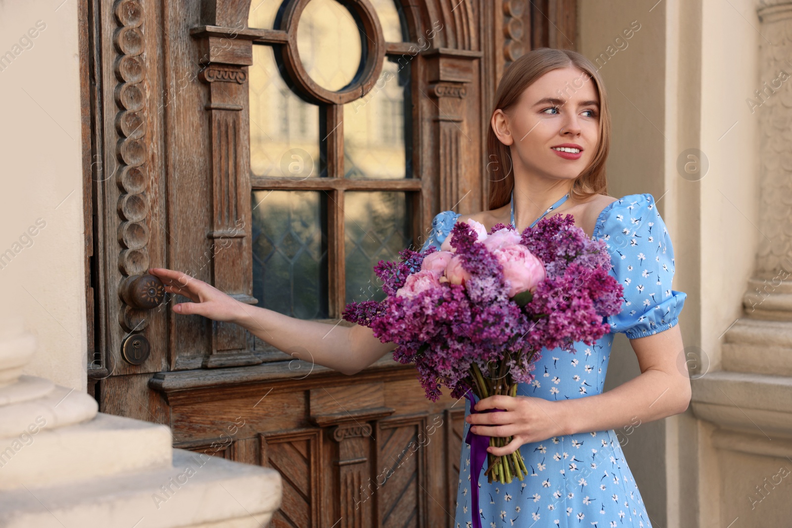 Photo of Beautiful woman with bouquet of spring flowers near building outdoors