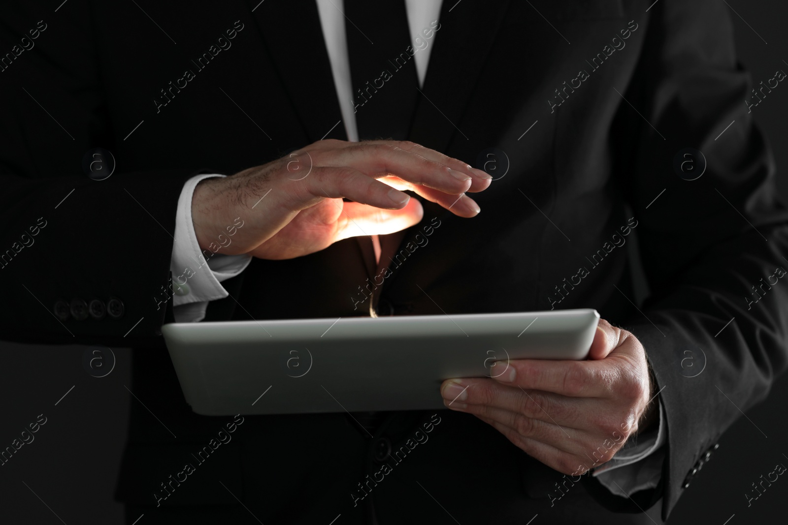 Photo of Closeup view of businessman using new tablet on black background