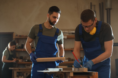 Photo of Professional carpenters working with wood in shop