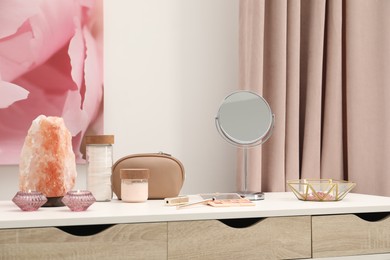 Dressing table with mirror, cosmetic products, jewelry and burning candles in makeup room