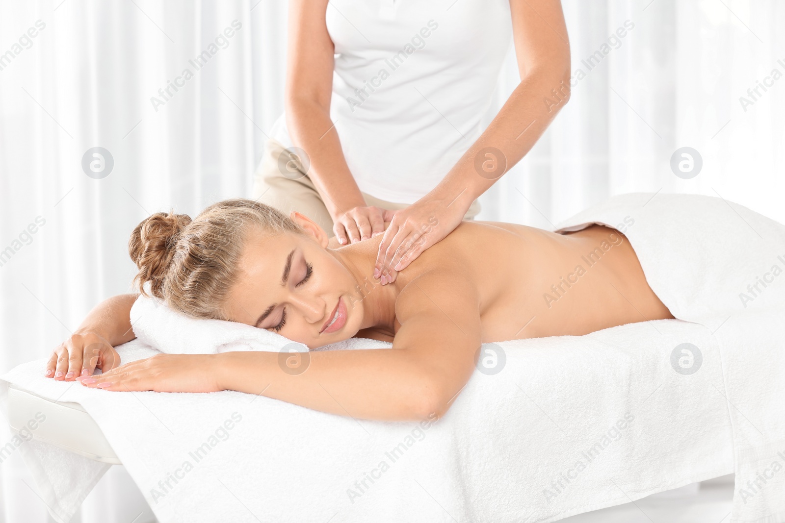 Photo of Relaxed woman receiving back massage in wellness center