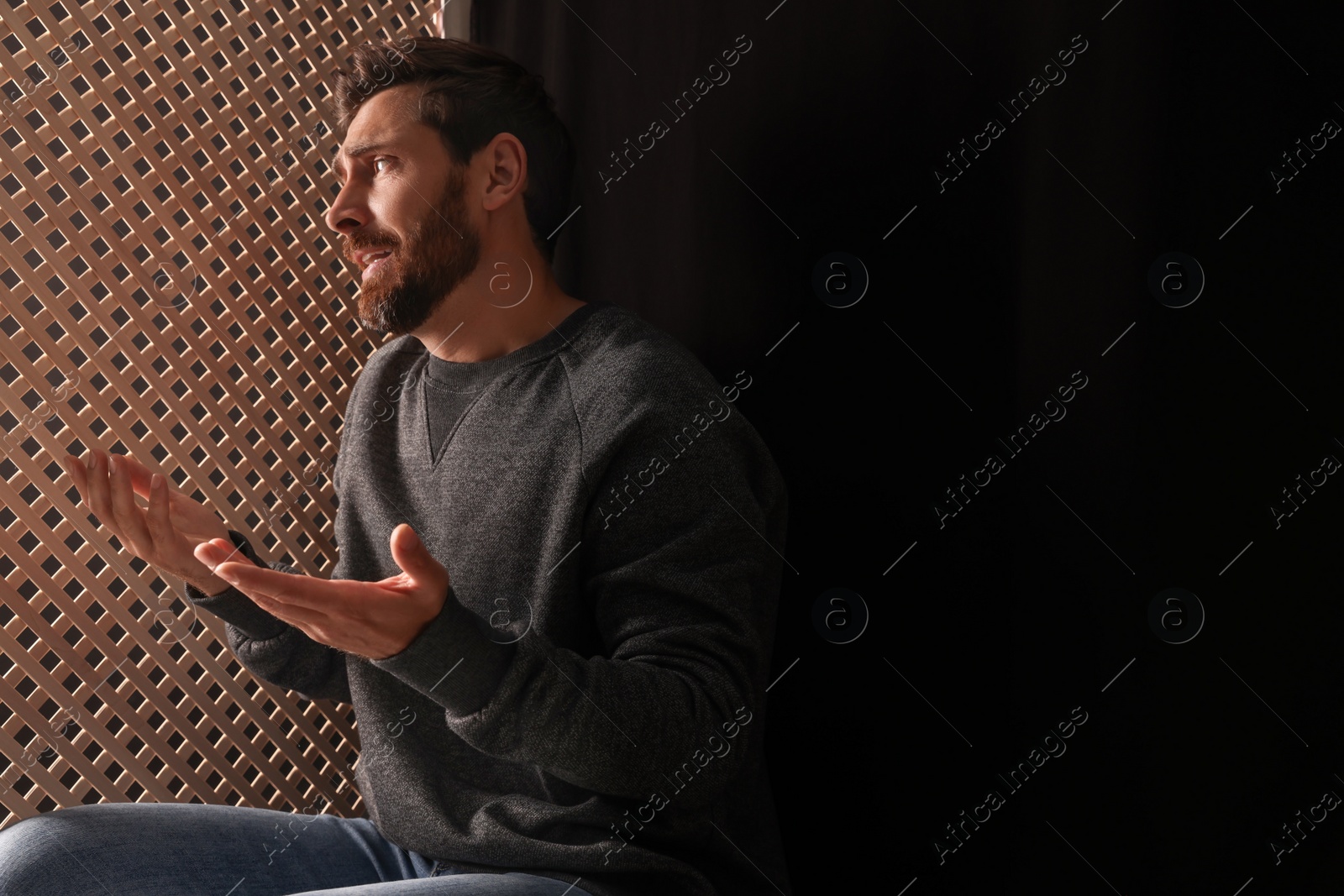 Photo of Upset man talking to priest during confession in booth, space for text