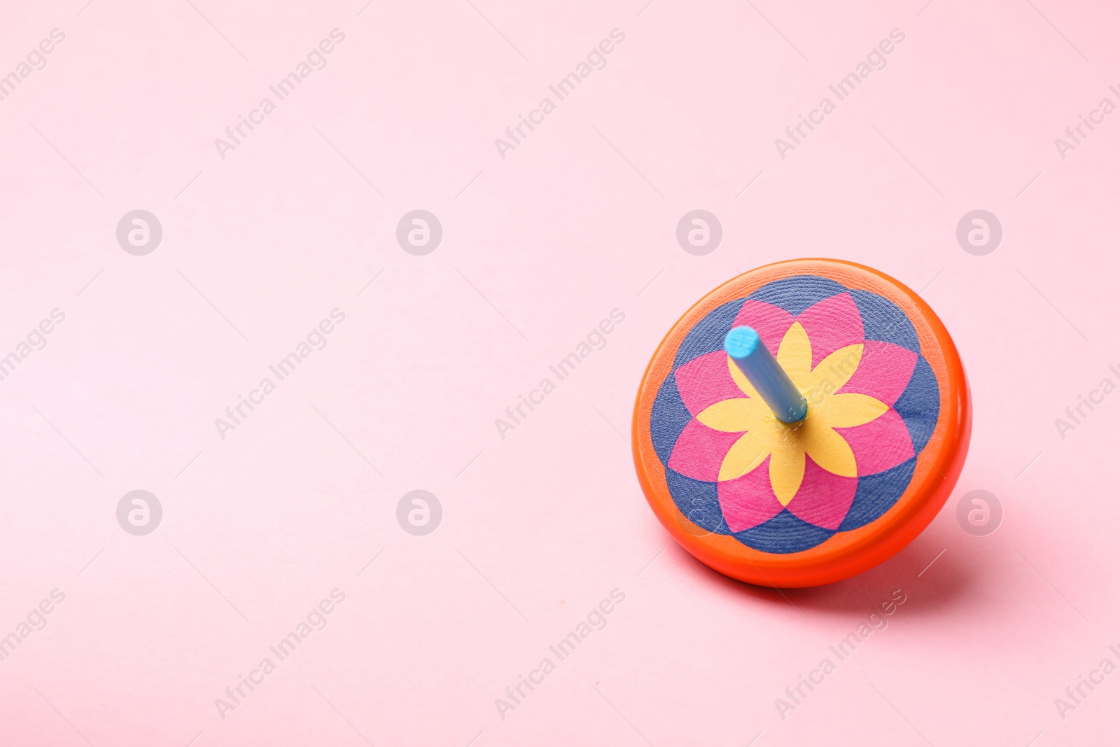 Photo of One colorful spinning top on pink background, space for text